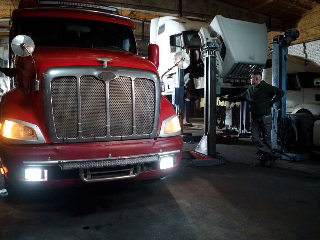 Truck raised on a lift inside a busy repair workshop