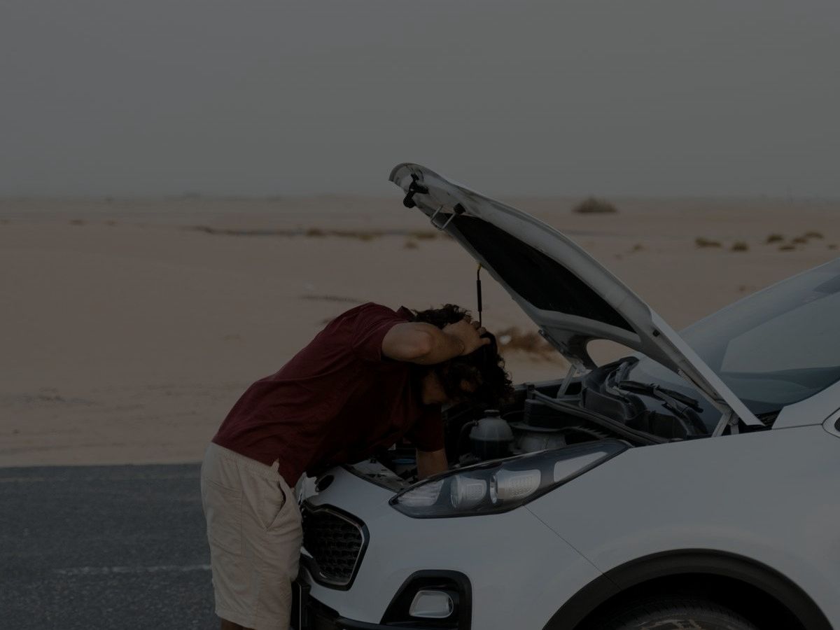 Driver checking under the hood of a car stopped at the roadside